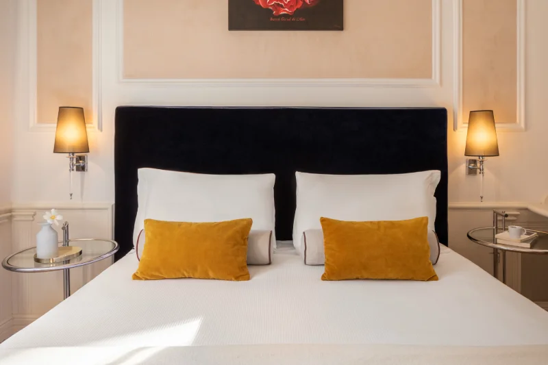 Classic double bed with blue headboard, ochre cushions and reading lights near the Rome Opera House - The Hotel Britannia, BZAR hotels in Rome